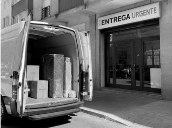 Furgoneta descargando bultos en la puerta de un comercio